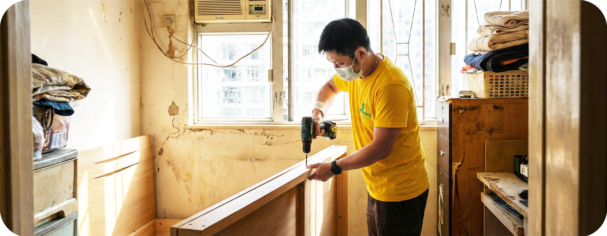 實惠搬屋師傅在劏房狹窄空間內使用電鑽進行床架拆卸。展示針對劏房及簡樸房的空間魔術師搬運服務，提供專業傢俬拆裝以適應窄門，並為細單位提供靈活實惠的搬屋報價。