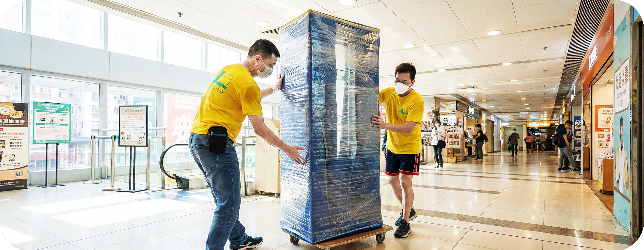 實惠搬屋師傅利用靜音板車在明亮的商場通道內推運已包裹的高身展示櫃。展示針對商場店舖、零售業及展覽會場的專業搬遷服務，強調配合商場規定的夜間搬運能力。