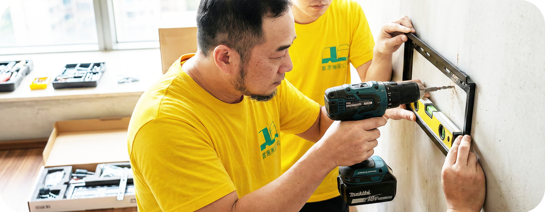 實惠搬屋師傅正在使用牧田 (Makita) 電鑽與水平尺進行上牆傢俬安裝。展示專業的傢俬拆裝與鑽牆服務，確保電視架或層架安裝精準水平，提供搬屋、打孔及還原的一站式搬運解決方案。