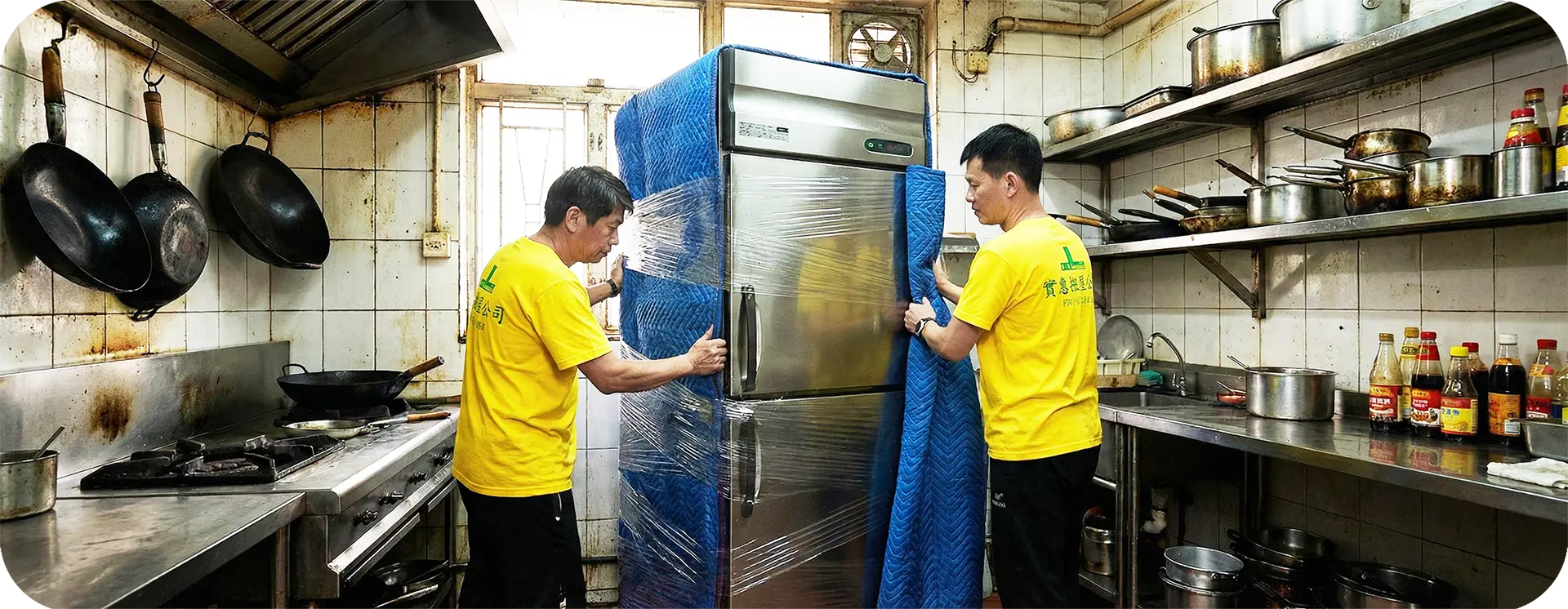 實惠搬屋師傅在商用廚房環境內，合力搬運已做好防護措施的大型不銹鋼商用雪櫃。展示針對食肆、餐廳及中央廚房的重型廚房設備搬運能力。